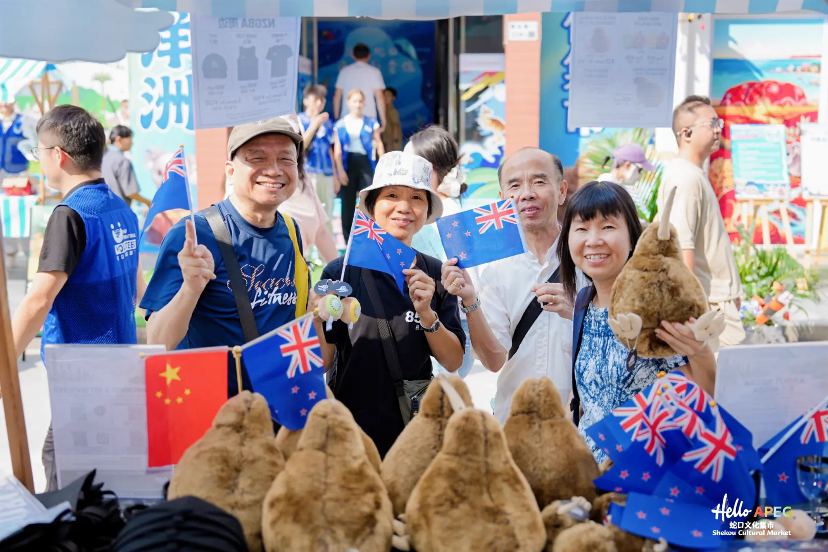 Visitors holding New Zealand flags and a plush kiwi bird